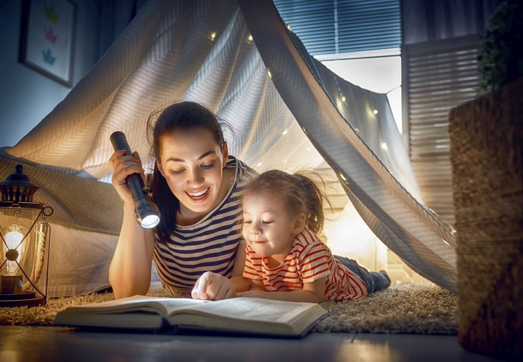 Elternzeit beantragen: Eine Frau liest mit ihrem Kind zusammen ein Buch