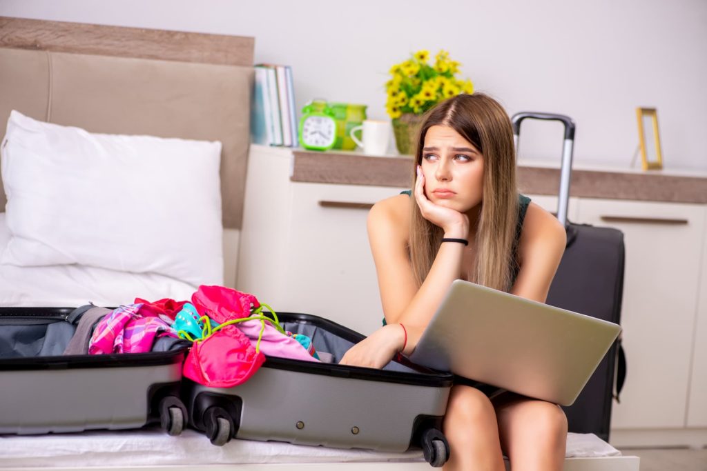 Genehmigten Urlaub streichen: Eine Frau mit gepacktem Koffer und Laptop