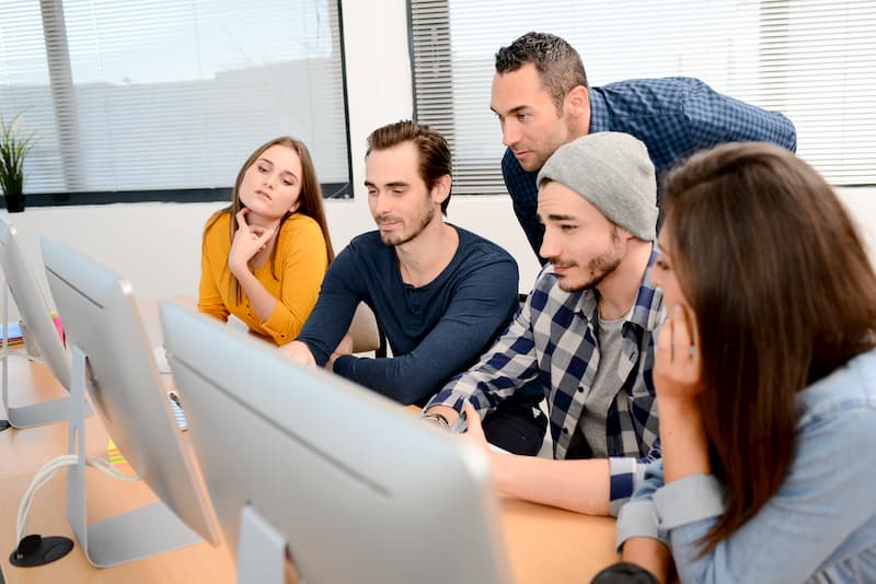 Junge Menschen sitzen vor einem PC und machen ein Traineeship