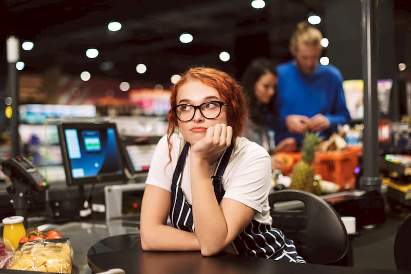 Eine Kassiererin hat Langeweile am Arbeitsplatz, das kann zum Boreout führen