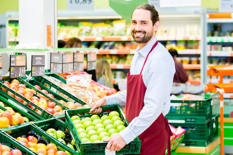 Ein beliebter Nebenjob ist das Auffüllen von Supermarktregalen, hier füllt ein Mann ein Regal mit Äpfeln auf