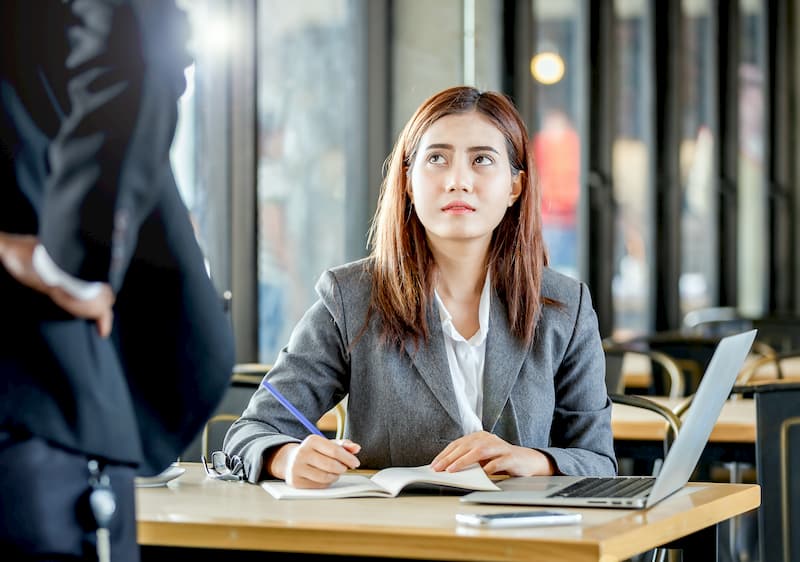 Eine Frau schaut traurig auf einen anderen Mitarbeiter nach einem Konflikt am Arbeitsplatz