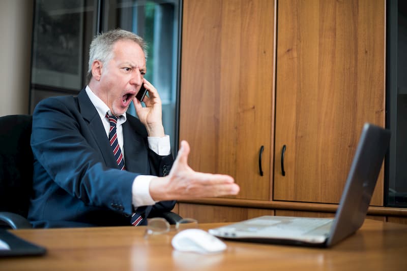 Ein Chef beleidigt einen Mitarbeiter am Telefon, ein Beispiel für Bossing