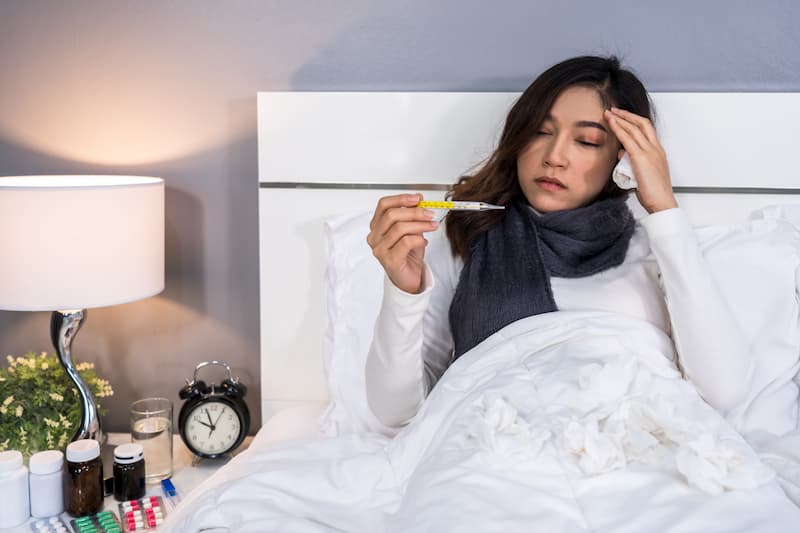 Eine Frau liegt krank im Bett und muss eine Arbeitsunfähigkeitsbescheinigung einreichen