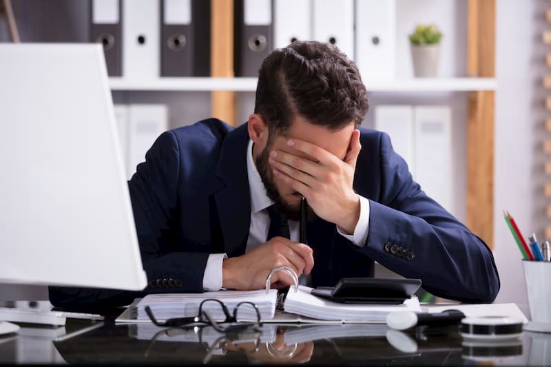 Ein Mann sitzt am PC und hält sich die Stirn, vielleicht kann ein Jobwechsel helfen