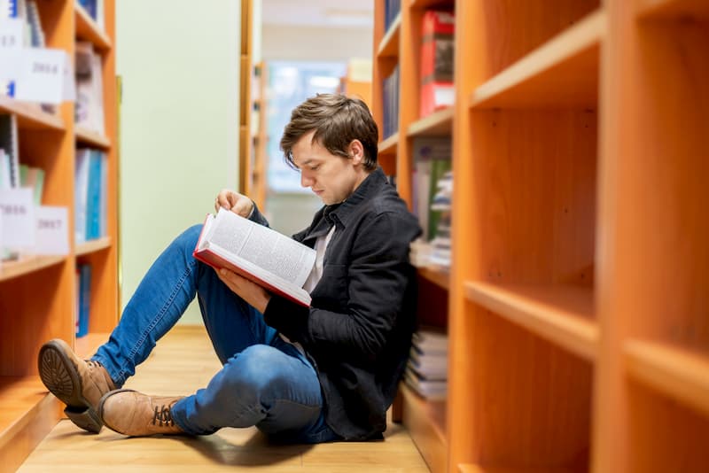 Ein Mann lernt im Rahmen der Bildungsteilzeit und liest ein Buch in der Bibliothek