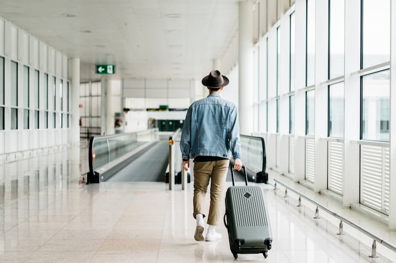 Ein Mann zieht seinen Koffer am Flughafen Richtung Terminal, er hat eine Urlaubsvertretung gefunden