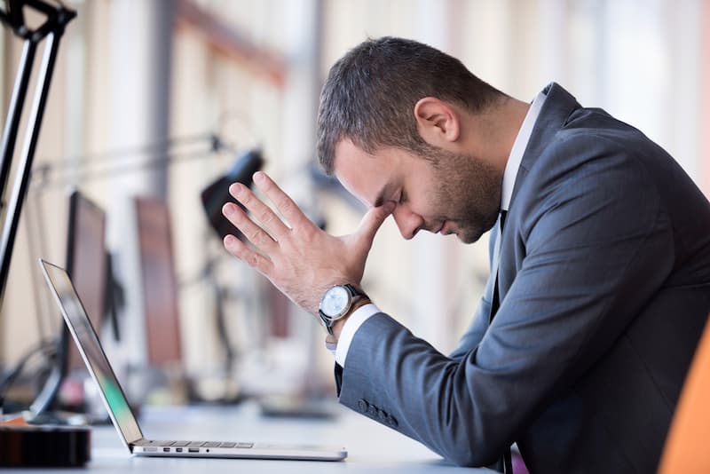 Ein Mitarbeiter sitzt traurig vor dem PC im Büro, er erhielt eine personenbedingte Kündigung