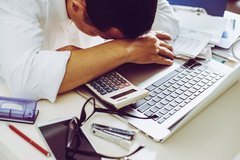 Ein Mann senkt den Kopf auf den Tisch und verzweifelt vor Stress im Job