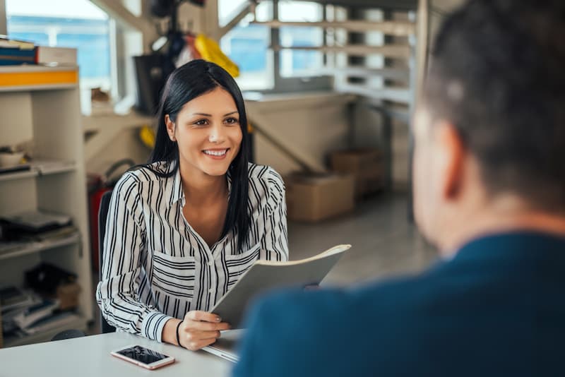 Eine junge Frau lächelt und hält ihr Arbeitszeugnis Muster in der Hand