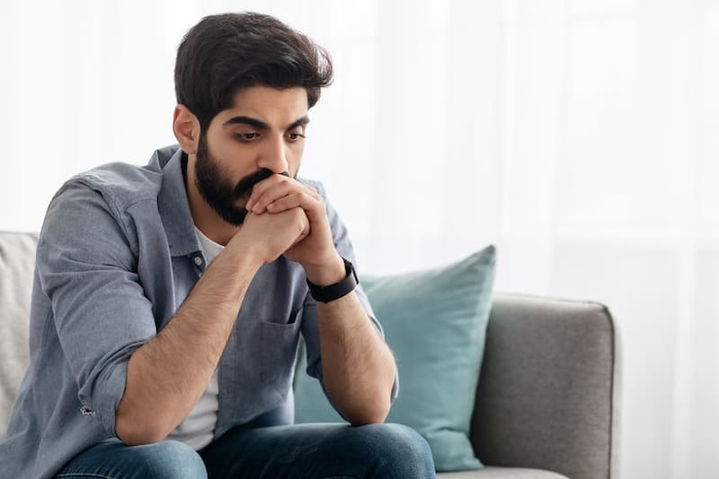 Ein Mann sitzt auf dem Sofa und denkt nach, denn er hat Bewerbungsangst