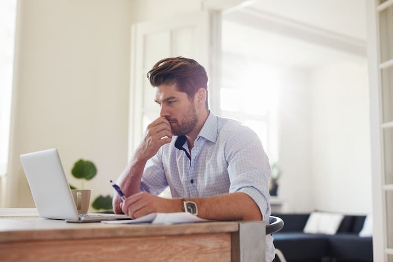 Ein Mann sitzt vor dem Laptop und ist bei der Jobsuche