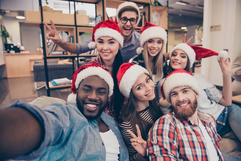 Mehrere Mitarbeiter mit Weihnachtsmützen, sie erhalten Weihnachtsgeld