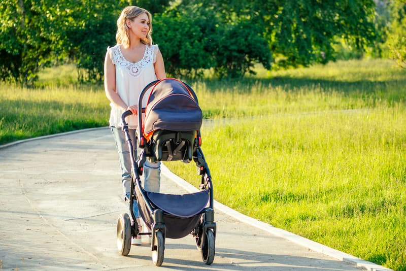 Eine Frau mit Kinderwagen, sie erhält Kindergeld während der Ausbildung