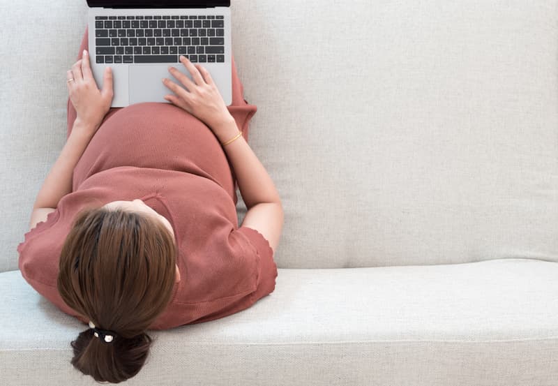 Eine Frau sitzt am Laptop, sie möchte sich schwanger bewerben