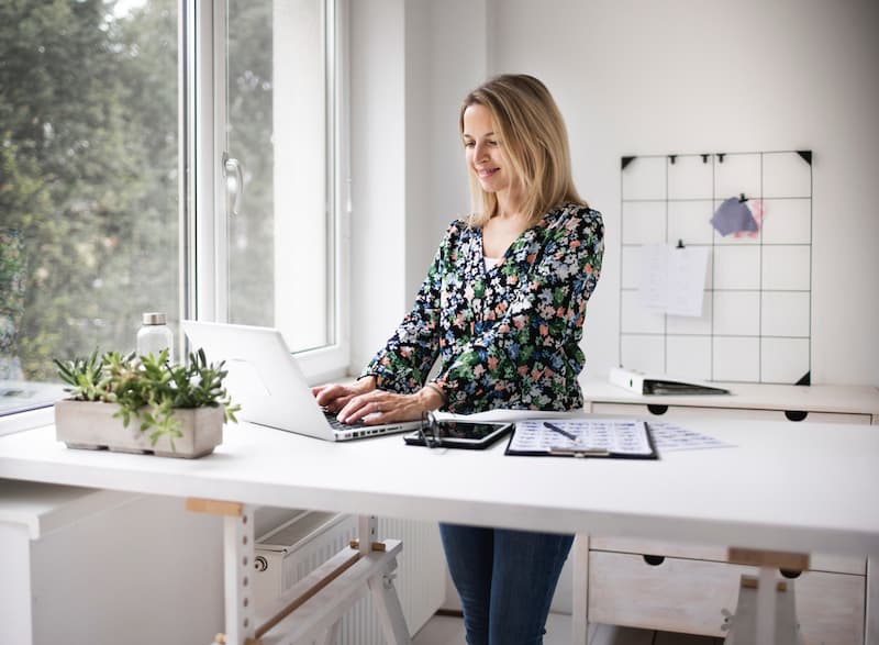 Eine Frau steht am Schreibtisch ein Beispiel für Ergonomie am Arbeitsplatz