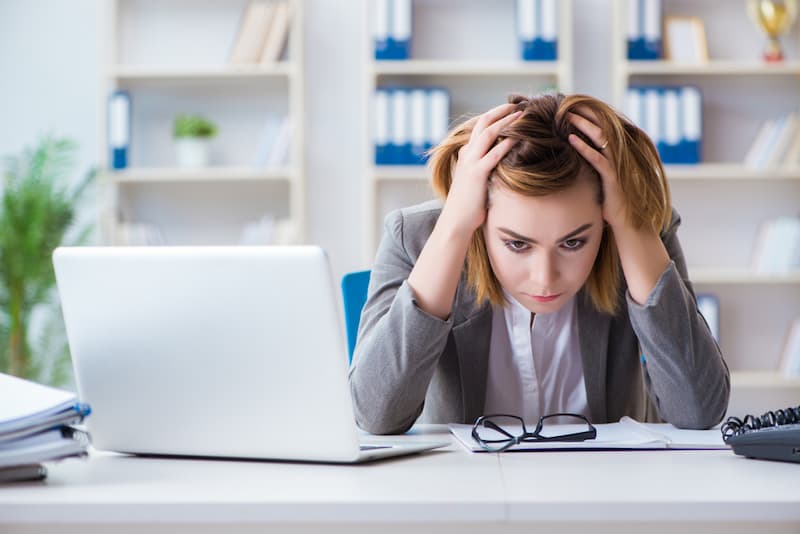 Eine Frau sitzt frustriert am Laptop, wie erhöht man die Frustrationstoleranz?
