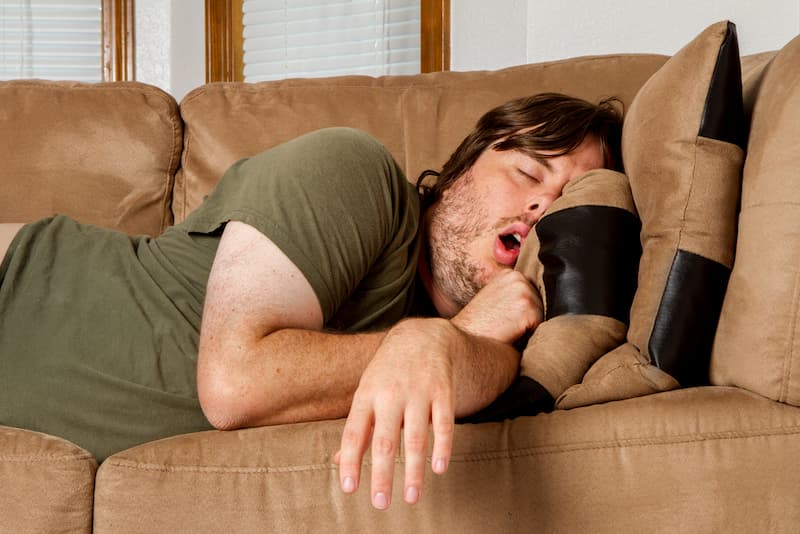 Ein Mann schläft auf dem Sofa, er macht krank