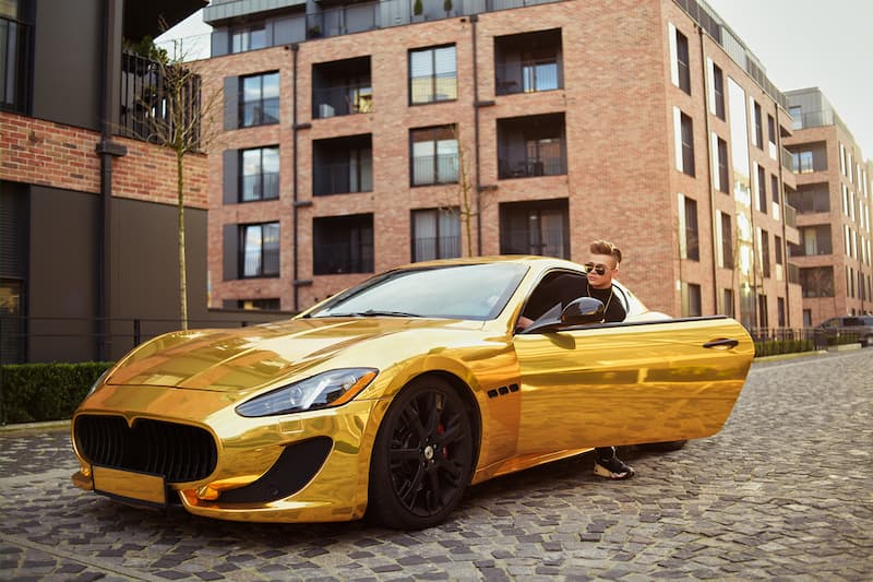 Ein Mann steigt aus einem goldenen Auto aus, was sind die bestbezahlten Berufe?
