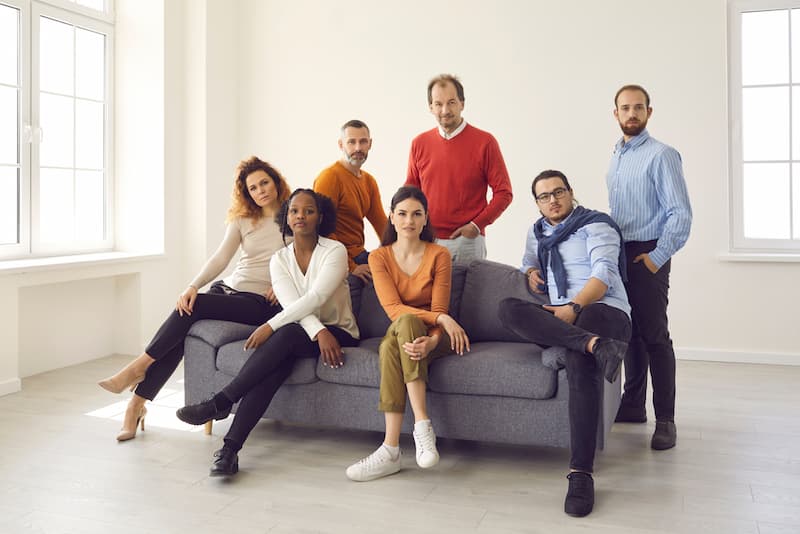 Verschiedene Mitarbeiter auf einem Sofa, ein Diversity Management sorgt für Unterschiedlichkeit