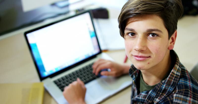 Ein junger Mann schreibt an einem Laptop eine Bewerbung für ein Schülerpraktikum