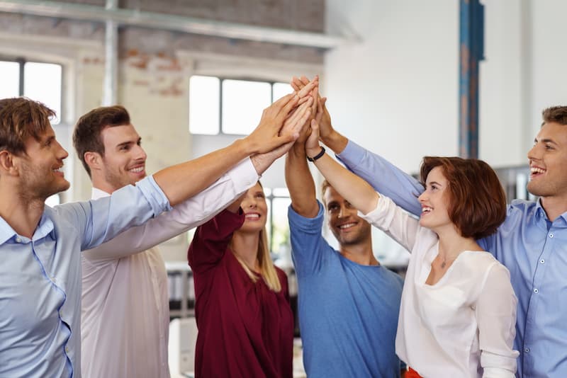 Ein Team hält die Hände zusammen, es gibt eine gute Mitarbeitermotivation