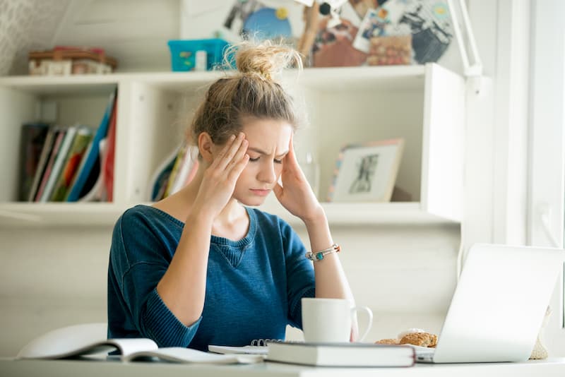 Eine Frau hält sich die Hände an die Schläfen, was versteht man unter Mental Load?