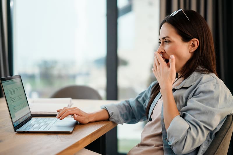 Eine Frau gähnt bei der Arbeit, wann kommt es zu Dienst nach Vorschrift?