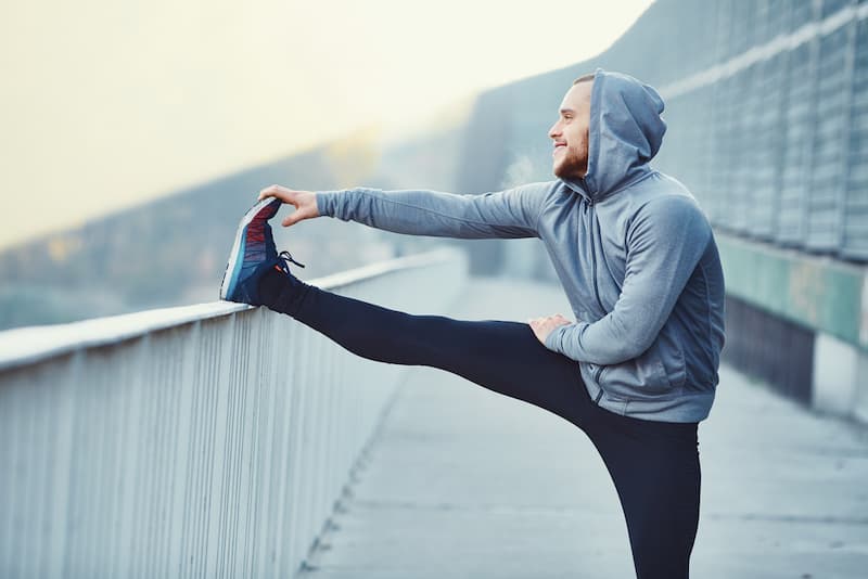 Ein Mann dehnt sich vor dem Laufen, wieso nutzt eine Routine?