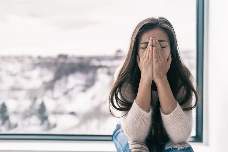 Eine Frau vergräbt das Gesicht in den Händen, ist eine Kündigung wegen psychischer Krankheit rechtens?