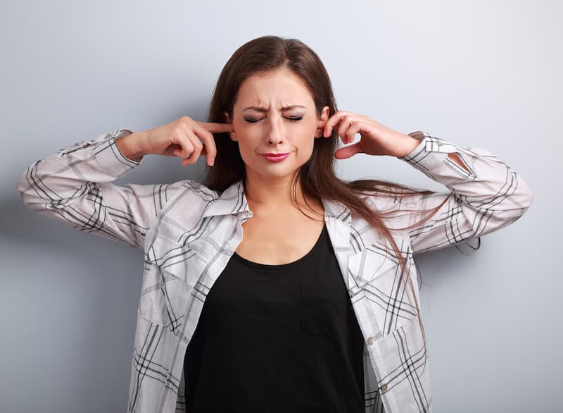 Eine Frau hält sich die Ohren zu, sie ist konfliktscheu