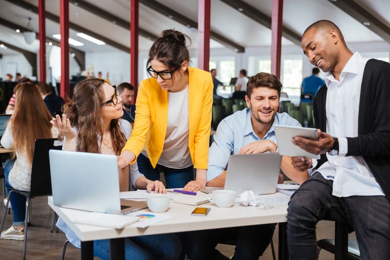 Mehrere Menschen an einem Tisch im Büro, was sind flexible Arbeitsplätze?