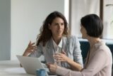 Zwei Frauen unterhalten sich am Arbeitsplatz, Oversharing -wenn eine Unterhaltung zu persönlich wird