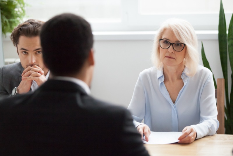 Mann sitzt bei Bewerbungsgespräch vor zwei Recruitern