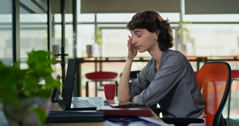 Junge Frau aus der Generation Z sitzt gelangweilt am Schreibtisch