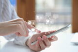 Eine Person hält ein Smartphone in der Hand. Mit der anderen Hand tippt sie auf den Touchscreen. Ein Symbolbild für virales Marketing.